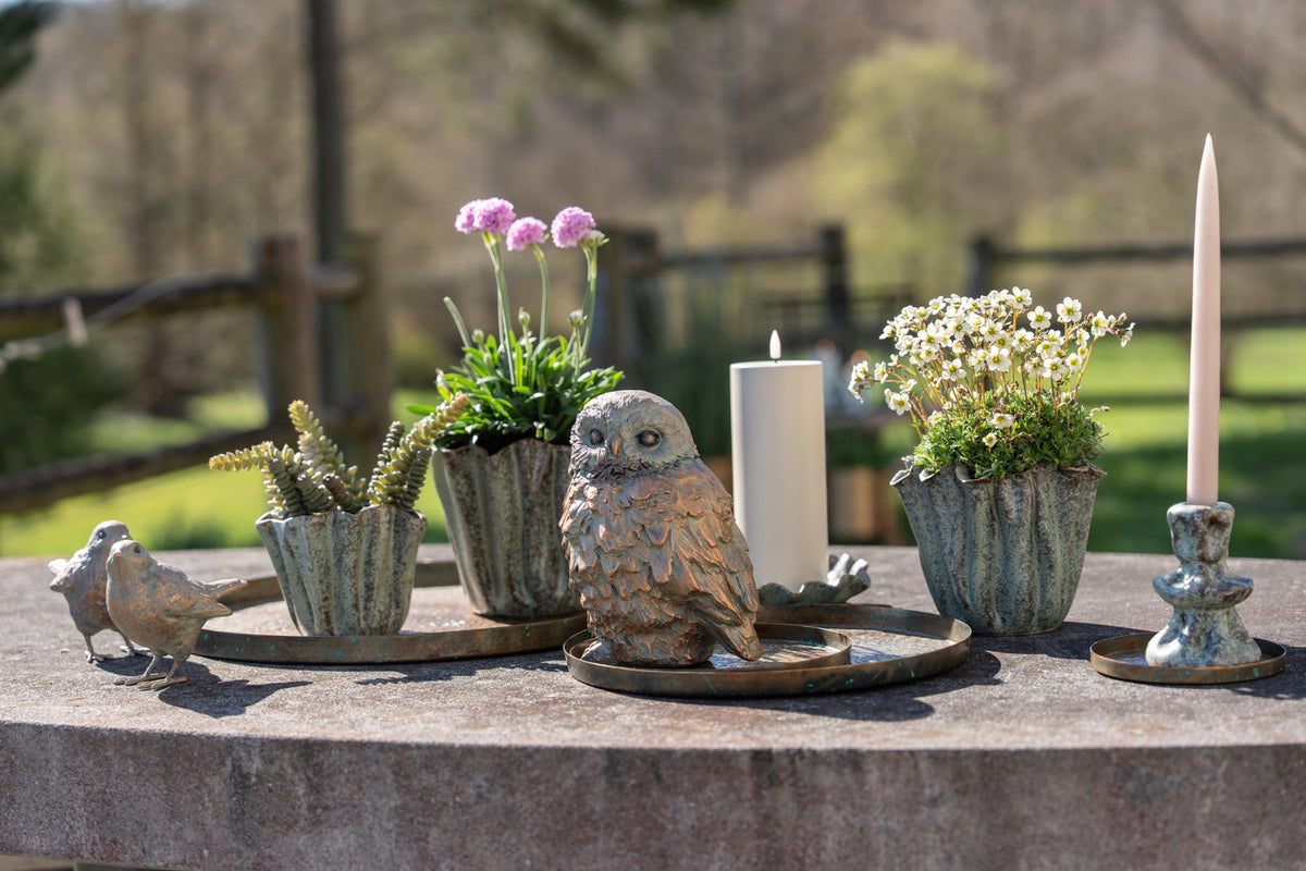 Rustikt metallbrett fra Speedtsberg brukt som dekorasjonsfat med små blomster, lys og naturpynt på et utendørsbord