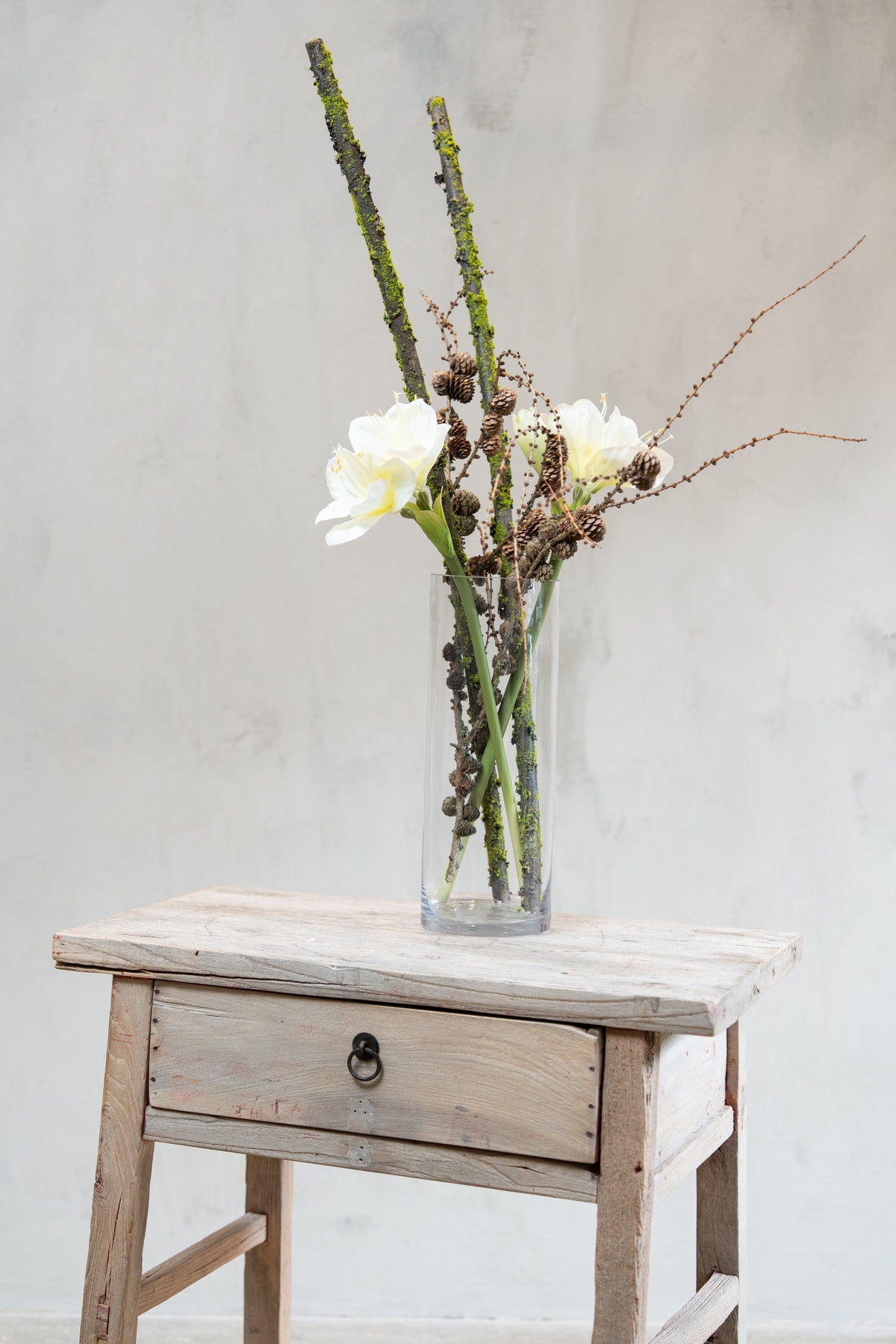 Vase med konglegrener, mosegrener og kunstige hvite amaryllisblomster fra Speedtsberg