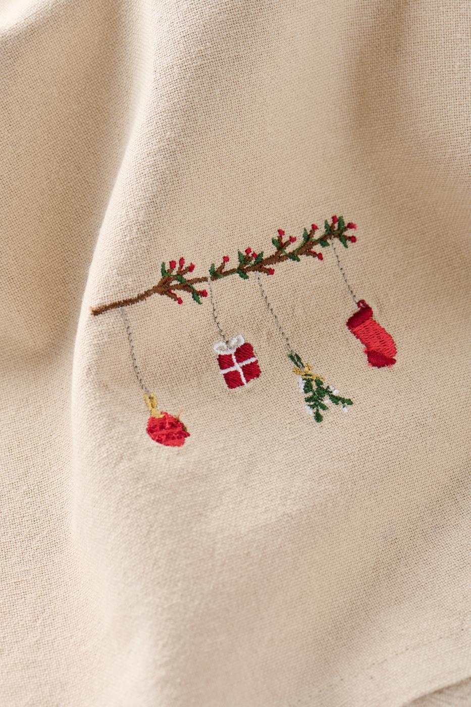 Motivet på linfarget stoffserviett med hengende julepynt i form av en Tradition-gren fra Ib Laursen, sett tett på