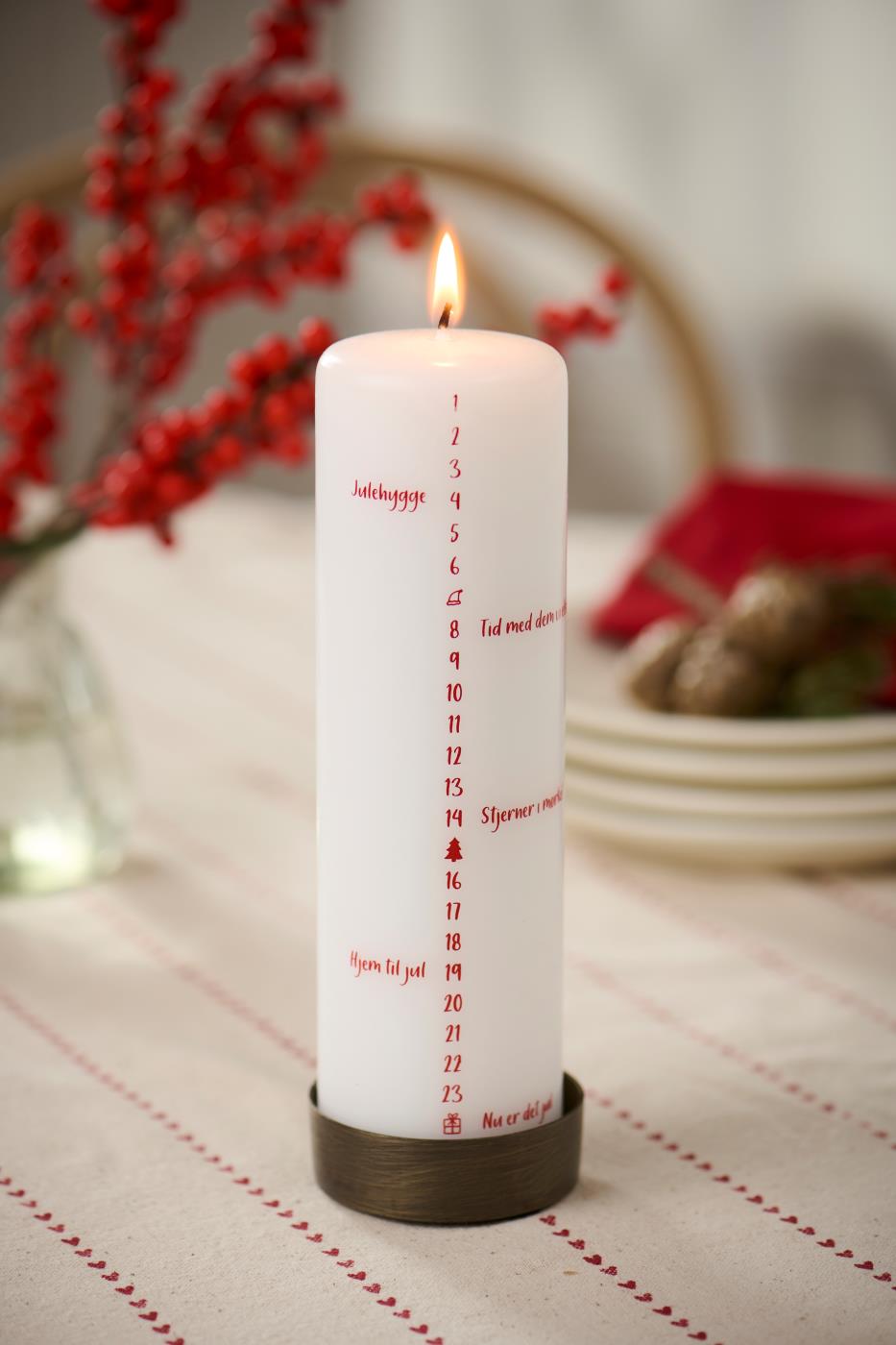 Hvidt kalenderlys med røde tal og små hyggelige julebeskeder på