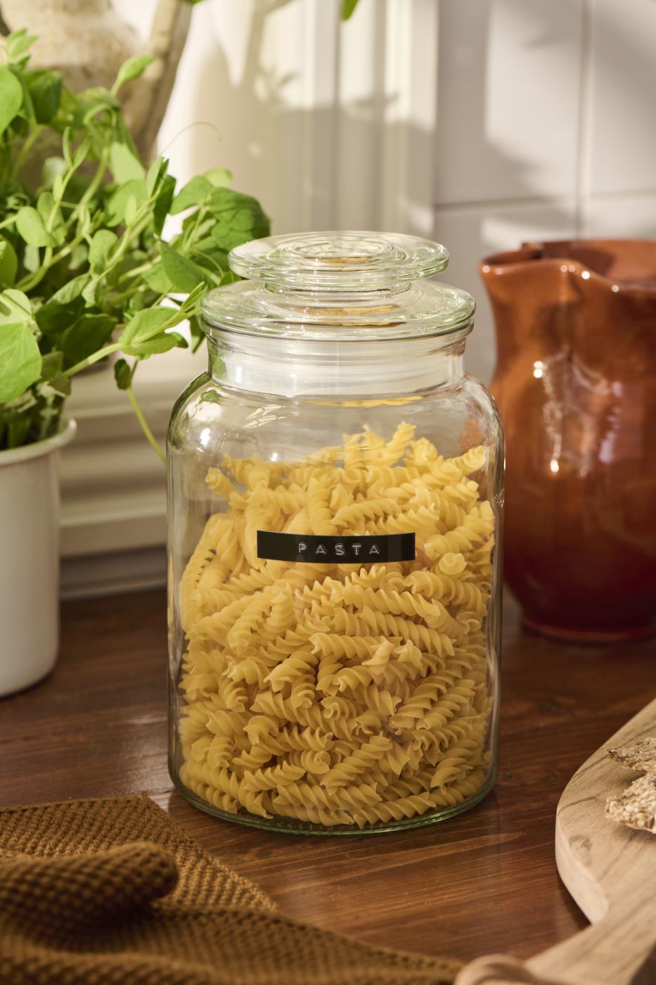 Oppbevaringsglass med lokk fylt med pasta på et rustikt kjøkkenbord