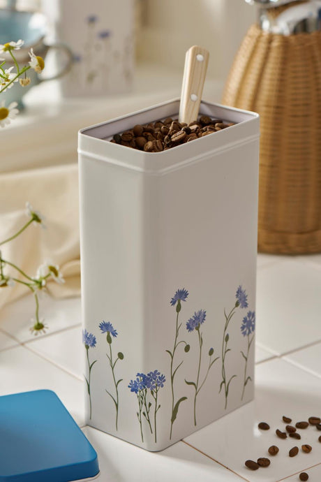 Dåse med kornblomstmotiv, fylt med kaffebønner.