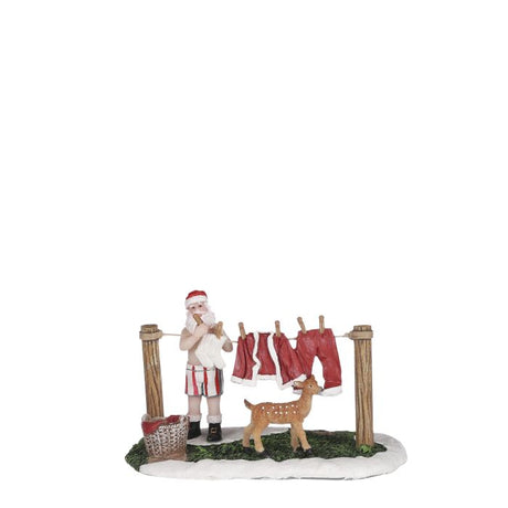 Julemanden hænger sit julemandstøj op på tørresnoren, vasketøjskuren og et dådyr står ved ham. En sød figur til julelandskabet fra Luville. 