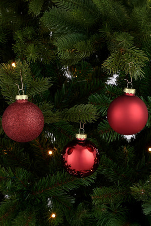 Matt, blank og glitrende julekule i glass hengende på juletre