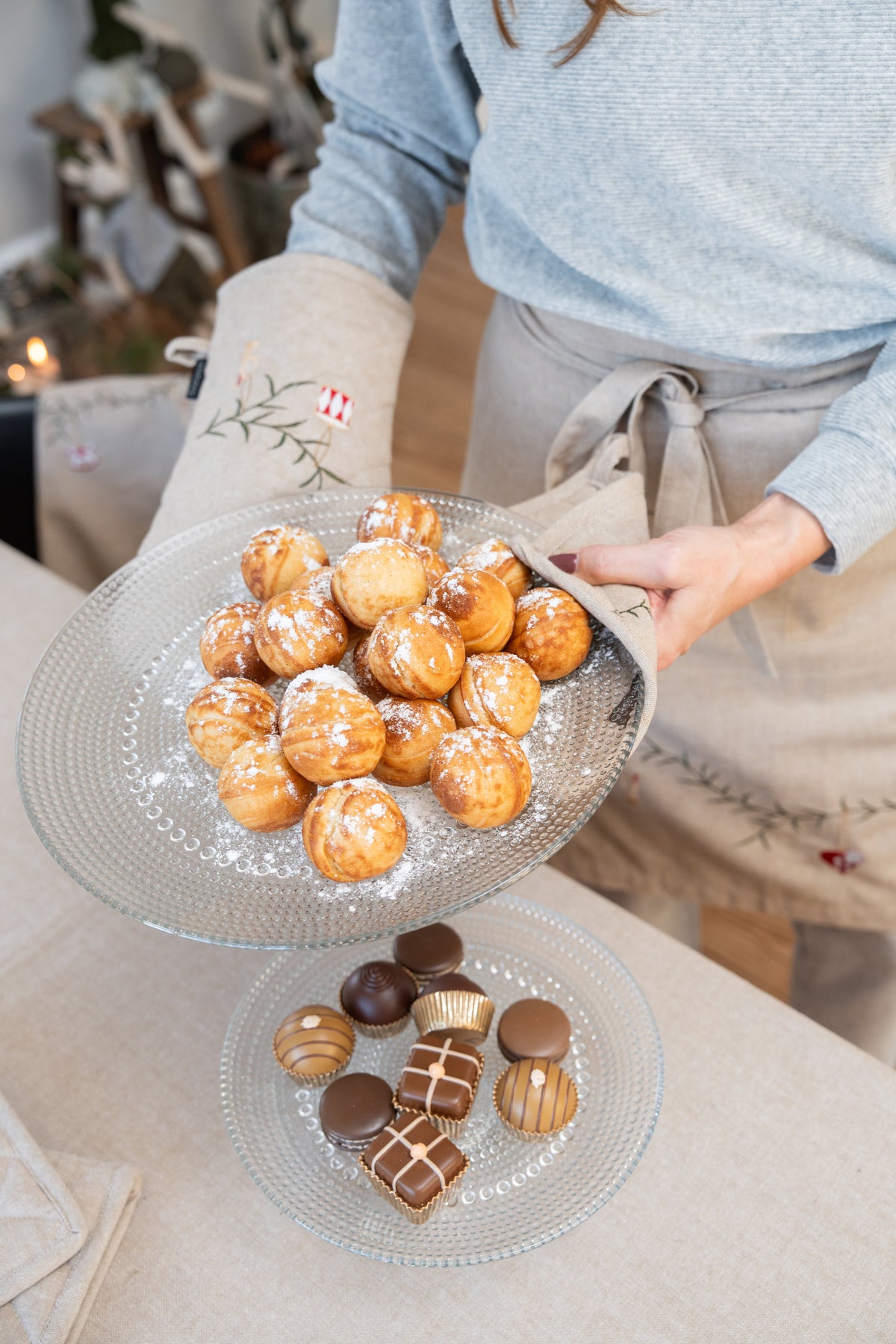 Varme æbleskiver settes på bordet med grillvott og gryteklut i quiltet bomull,