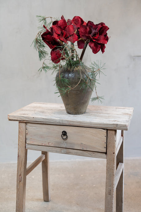 Bukett av kunstige amaryllisstilker med vinrøde blomster og furugreiner i en vase