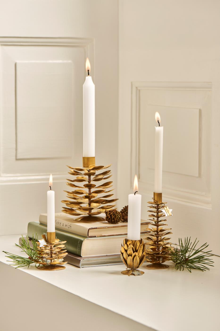 Flere størrelser af koglelysestager stående sammen med bøger 