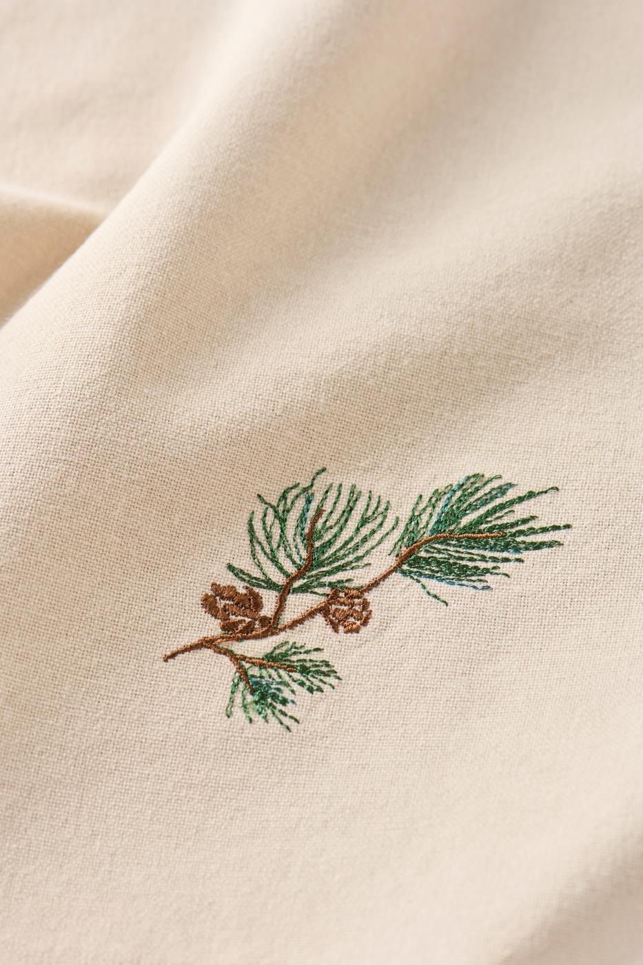 Motivet på stoffserviett Tradition med furugren og kongler fra Ib Laursen, sett tett på
