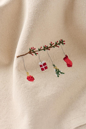 Motivet på linfarget stoffserviett med hengende julepynt i form av en Tradition-gren fra Ib Laursen, sett tett på