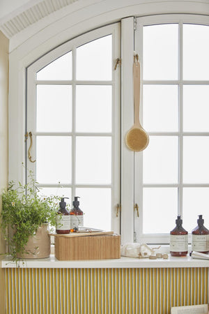ALTUM pleieprodukter fra Ib Laursen ved vinduet i et lyst baderom med naturlige materialer